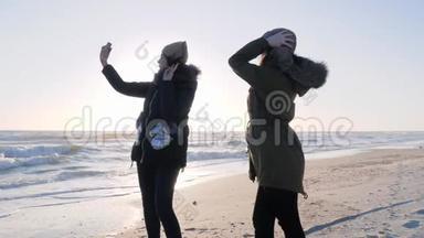 积极的娱乐<strong>活动</strong>，积极的女孩玩得开心，在阳光下在海洋海岸的<strong>手机</strong>上自拍。
